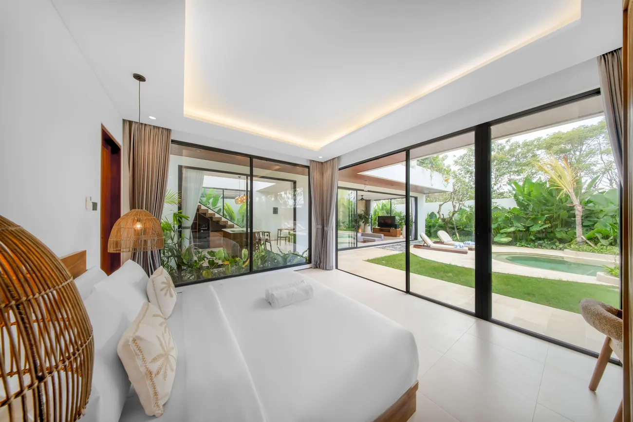 Chambre avec fauteuil suspendu en rotin ouverte sur le jardin